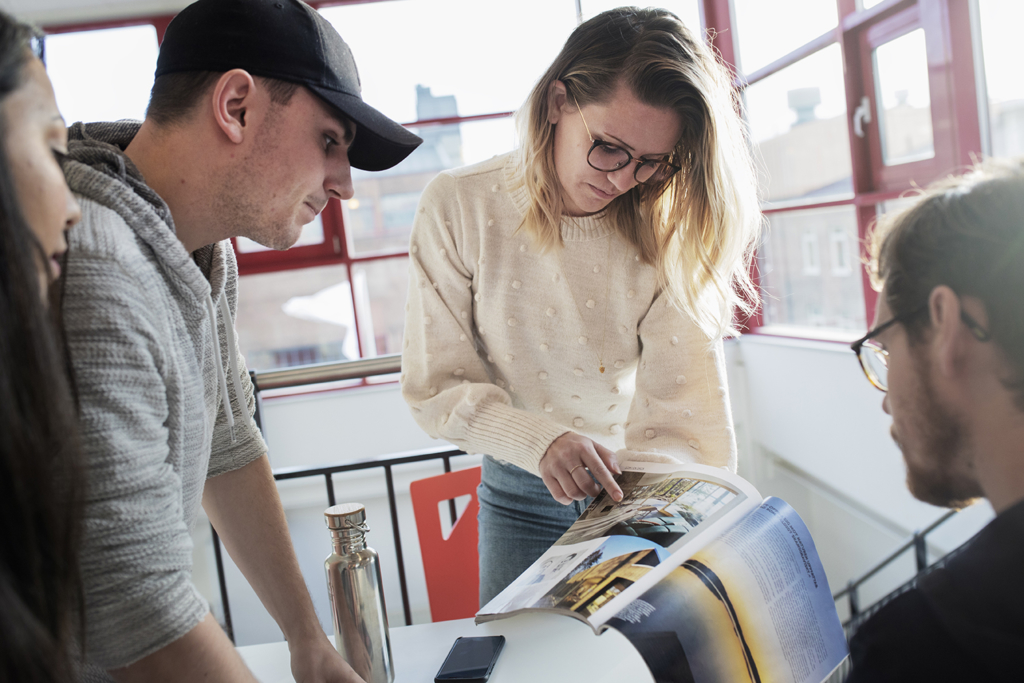 Fyra studerande pekar och tittar i arkitekturtidning.