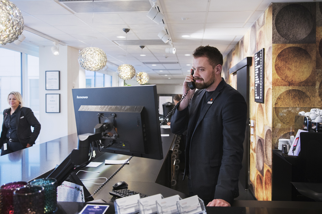 En man står i en reception och pratar i telefon.